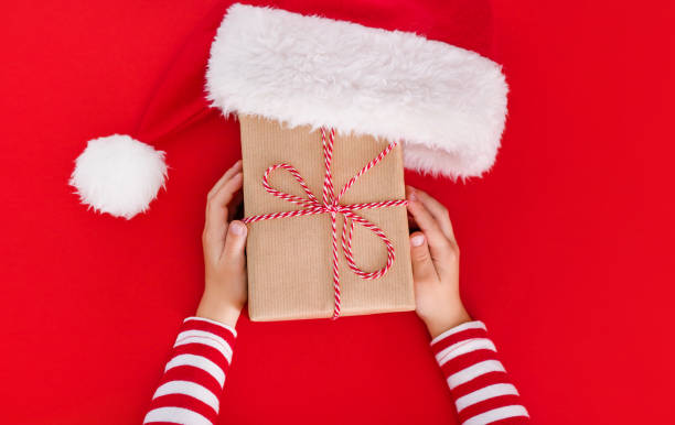 istock gift box in children's hands on a red background, presenting a gift, christmas background 1350467419