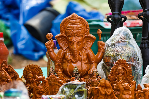 In focus of the small clay idol of lord Ganesha along with other god and goddesses at a road side vendor stall. Locals make their living selling these idols during different festivals.