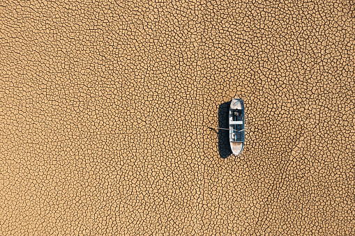 Aerial view of a fishing boat on a drought dry lakebed.