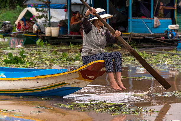 Young woman looking at the camera while fixing fish nets in Kampong Phluk on Tonle Sap lake