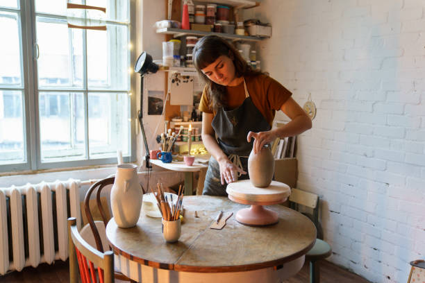 istock Creative girl art student or workshop owner creating potter vase in studio. Female work with clay 1350472992