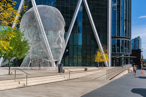 Calgary, Alberta, Canada - 27 September 2021: Wonderland sculpture by Jaume Plensa in front of the Bow tower.
