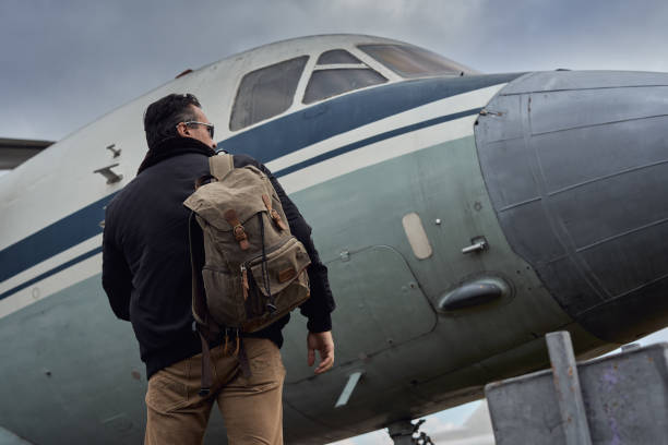 istock Oldschool pilot in the bomber jacket posing near the aircraft 1350480913