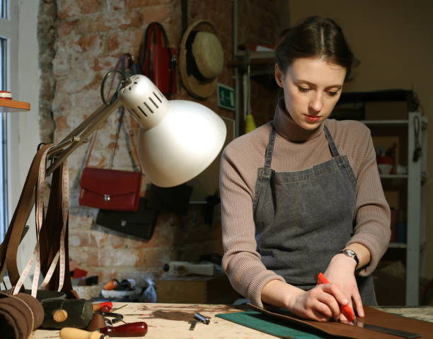 istock young brunette woman works in a bag making studio, cuts out details 1350481990