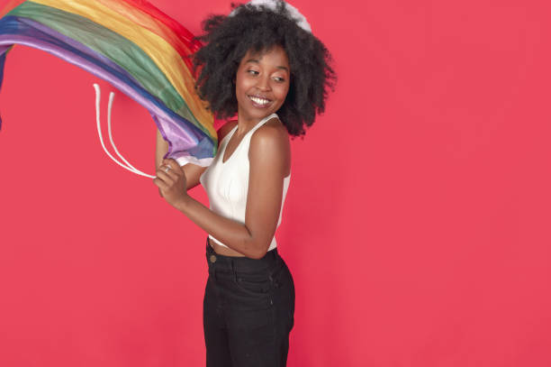 young black woman smiling with an LGBT flag standing stock photo