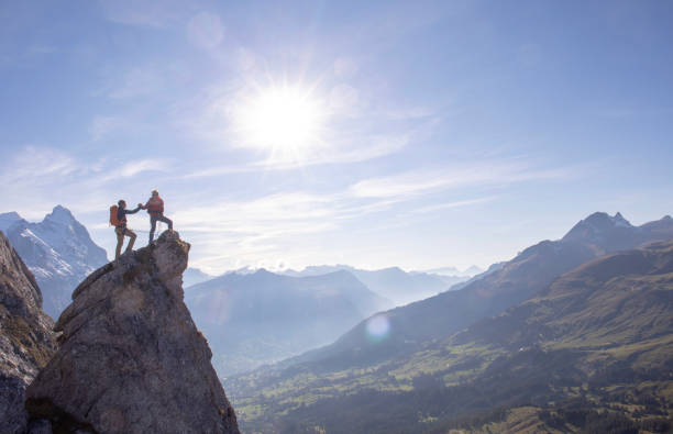 alpinistes high-five sur le pinacle rocheux ensoleillé - mountain peak switzerland grindelwald bernese oberland photos et images de collection