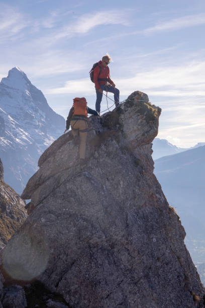 un alpiniste assure un ami grimpant sur le pinacle rocheux - european alps mountain mountain peak rock photos et images de collection