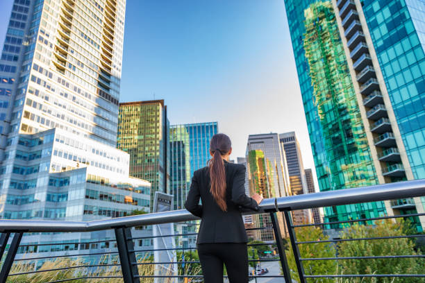 Business woman in city center looking at view of skyline skyscrapers in Vancouver downtown , Canada. Businesswoman from the back pensive thinking about success and future in career and job stock photo