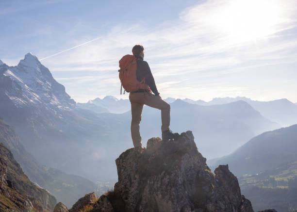istock Mountaineer relaxes on rock pinnacle in the sunshine 1350486015