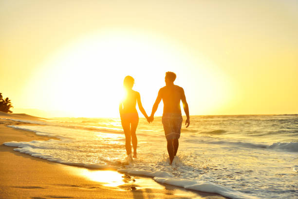 ビーチの夕日に恋にロマンチックなハネムーンカップル - swimming trunks swimwear summer bikini ストックフォトと画像