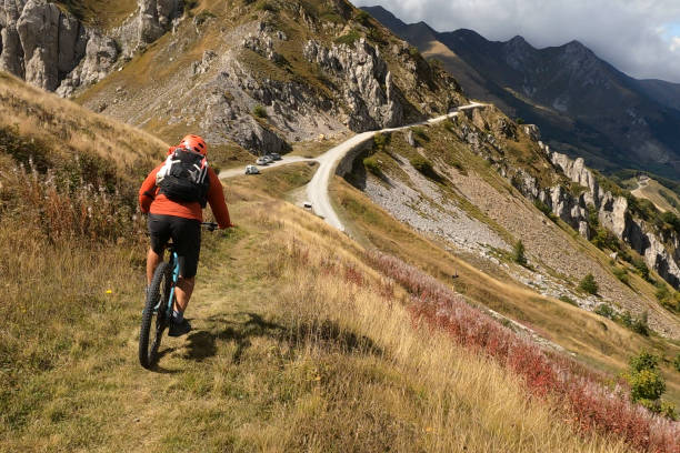 istock Mountain biker follows trail on grassy mountain ridge 1350487168
