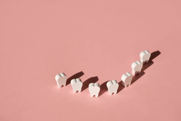 istock Teeth stand on a pink background in a row, forming a smile. 1350487606