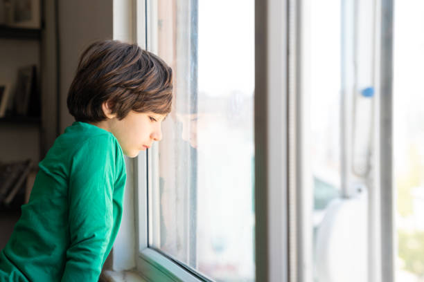 istock Photo Of Elementary Schoolboy Looking Through Window 1350491319