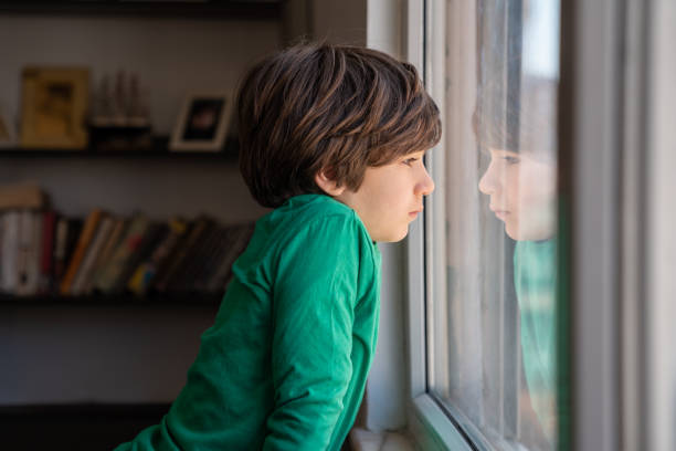 istock Photo Of Elementary Schoolboy Looking Through Window 1350491342