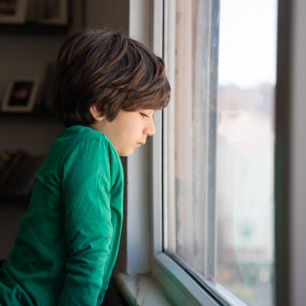 istock Photo Of Elementary Schoolboy Looking Through Window 1350491345