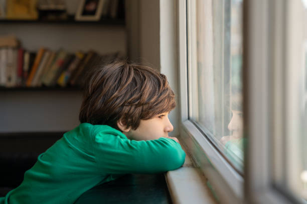 istock Photo Of Elementary Schoolboy Looking Through Window 1350491374