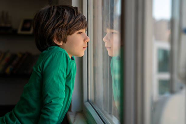 istock Photo Of Elementary Schoolboy Looking Through Window 1350491376