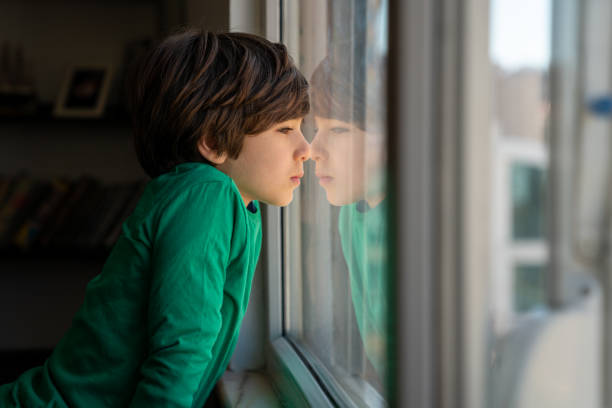 istock Photo Of Elementary Schoolboy Looking Through Window 1350491377
