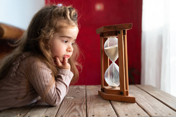 Photo Of Little Preschooler Girl Watching Hourglass Sand stock photo