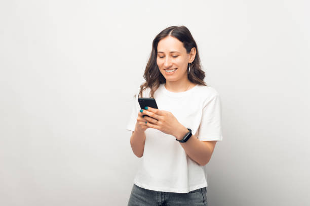 istock Joyful beautiful woman is texting on her phone while smiling. 1350492640