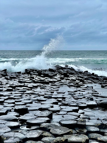 Ocean sea spray over Giant’s Causeway rocks in Country Antrim, Northern Ireland (United Kingdom). Waves crash into lava formations.