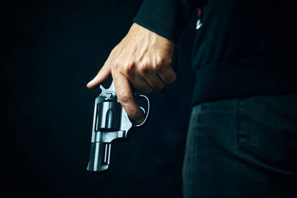 istock Man in dark clothing is holding gun. 1350500052