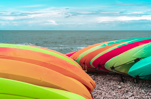Kayaks of different colors stacked on the shores of Atlantic ocean in Etretat, Normandy