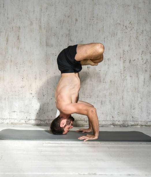 istock A young man is doing yoga. Yoga coach on a light background. 1350500746