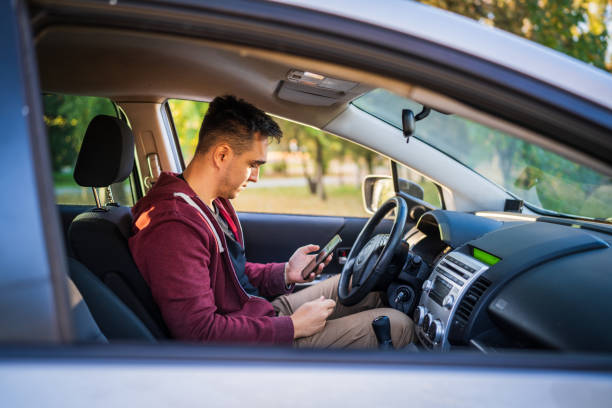 istock Side view of young caucasian man checking mobile phone for messages or navigation app for destination while sitting in car driving or parking real people travel concept 1350503134