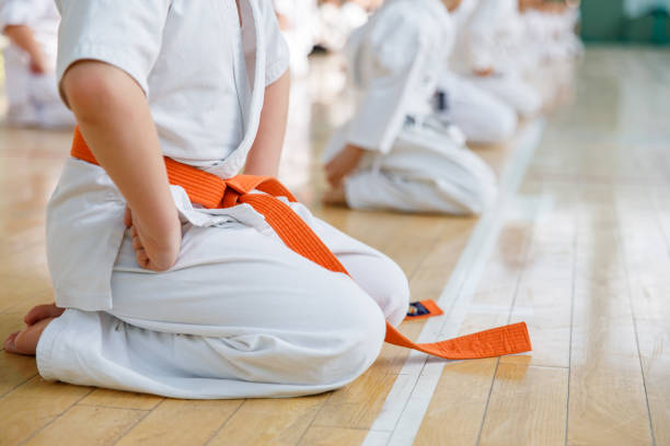 los estudiantes de karate entrenan en la sala de artes marciales. entrenamiento de la escuela de artes marciales en el gimnasio - karate child judo belt fotografías e imágenes de stock