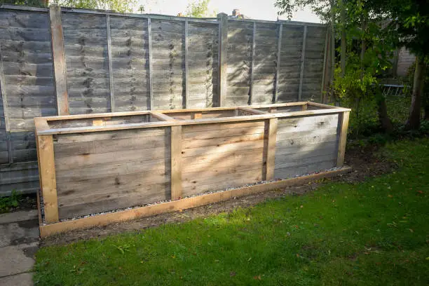 Empty large tall deep wooden garden vegetable box planter. Ready for filling with soil and planting all types of home grown vegetables such as carrots and potatoes.