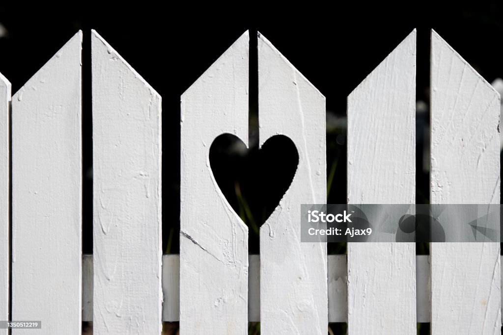 Heart shape cut out of white suburban residential fence A fence outside the yard of a house in the suburbs with a love heart shape cut out. Neighbor Stock Photo