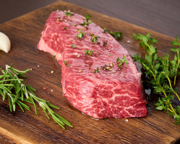 bistecca cruda di striploin con rosmarino, timo e aglio su tagliere di legno. - strip steak steak beef raw foto e immagini stock