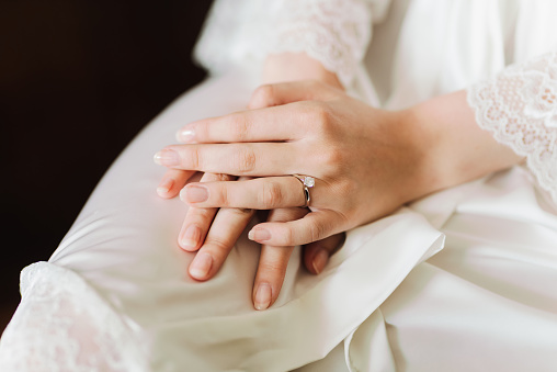 Bride's hands with an engagement ring on them with a beautiful gemstone.