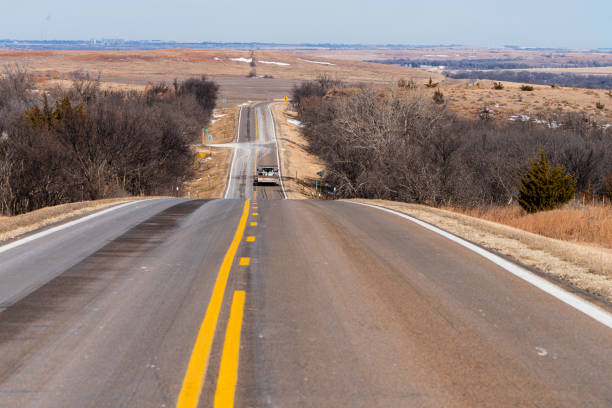 Highway between the agricultural harvested fields in Kansas, USA, in the winter sunny day.