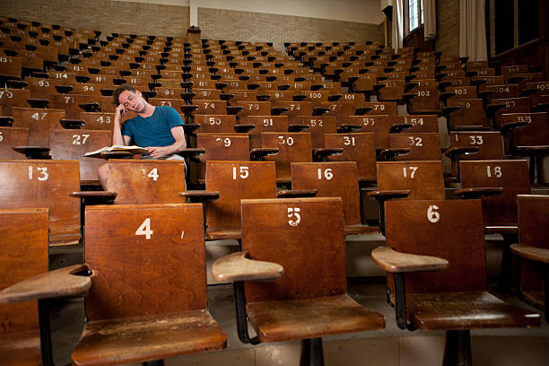 Tired University Student Male university student asleep in a large lecture hall male college student sleeping through lecture stock pictures, royalty-free photos & images