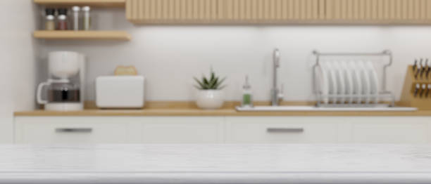 istock Close-up white granite kitchen countertop for montage over blurry white and wood kitchen 1350529825
