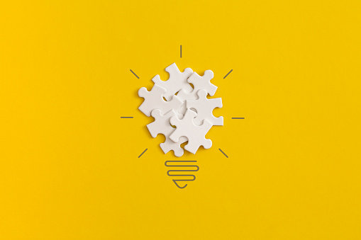 Light bulb from puzzles on yellow background. Inspiration and creative idea concept. Top view with copy space. Flat lay composition.