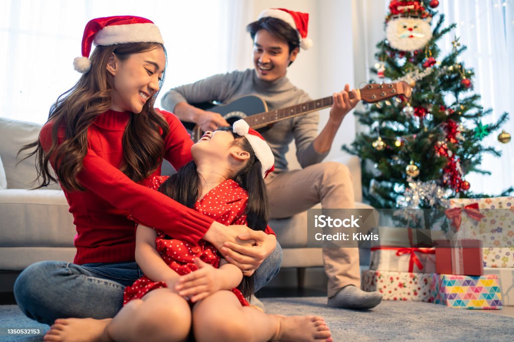 Asian lovely family member enjoy sing Christmas song together at home. Young little daughter feeling happy and excited to celebrate holiday Christmas Thankgiving party together with parents in house. Christmas Stock Photo