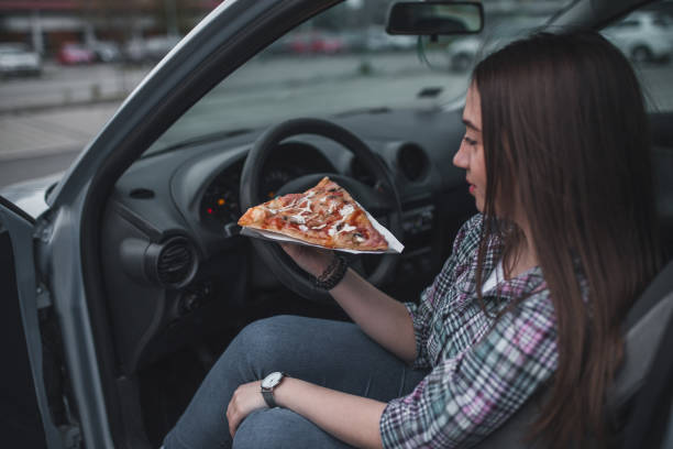 istock Young woman eating pizza in her car 1350534891