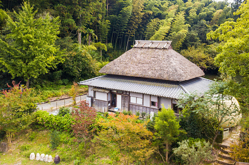 An aerial view of an old style traditional Japanese house with straw roof in the country side with nothing but nature all around.
