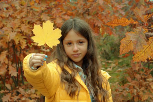 Autumn, girl holding a yellow maple leaf