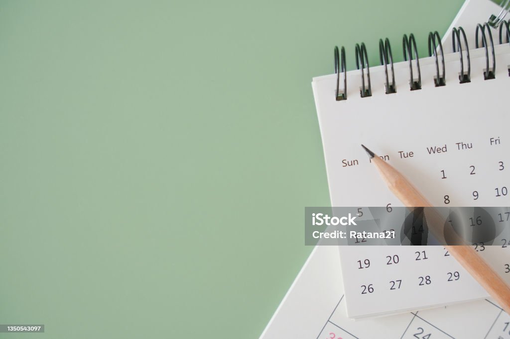 top view of white calendar and sharpen brown pencil on green background, schedule, timeline, planning concept Calendar Stock Photo