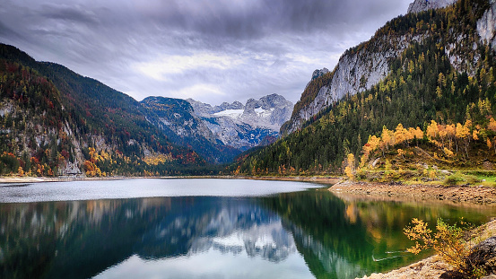 View of idyllic colorful autumn scenery with Dachstein Mountain at Lake Gosau in Austria