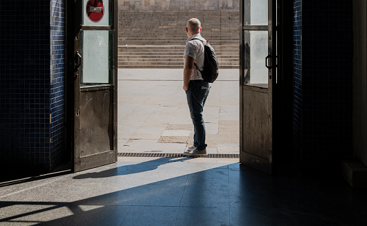 Adult an standing in the entrance of a public station in a sunny day