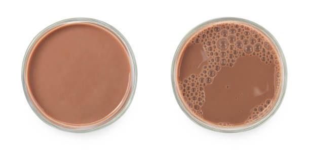 istock Chocolate milk puddle in glass isolated on white background. 1350551161