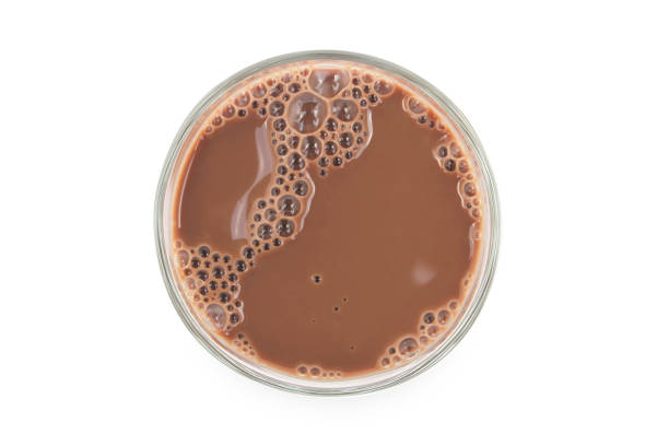 istock Chocolate milk puddle in glass isolated on white background. 1350551165