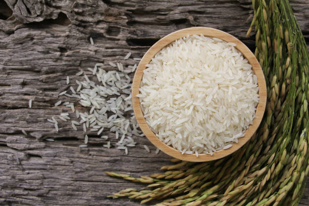 Thai Jasmine rice  (white rice) in wooden bowl and on wooden table. stock photo