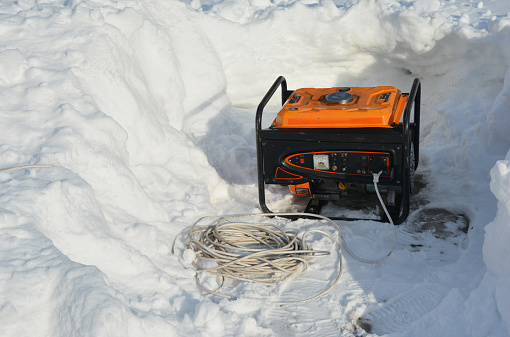 Un generador portátil, generador de energía de respaldo alrededor de la nieve después del clima invernal severo, ventisca y tormenta de nieve. Uso de un generador móvil para proporcionar energía después del clima nevado. photo