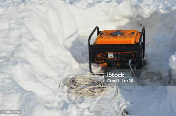 A Portable Generator Backup Power Generator Around Snow After Severe Winter Weather Blizzard And Snow Storm Using A Mobile Generator To Provide Power After Snowy Weather Stock Photo - Download Image Now